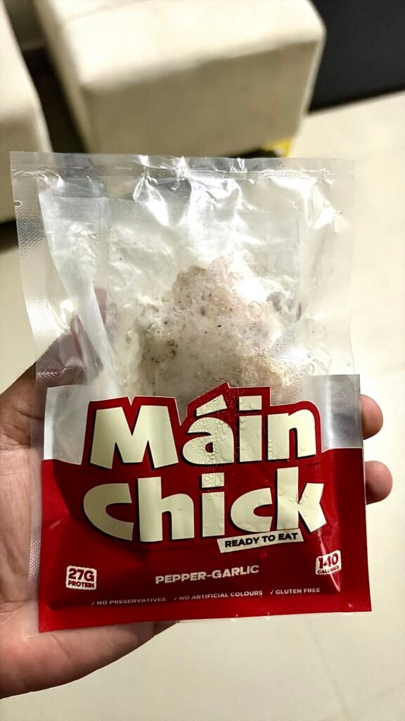 Hand holding a Máin Chick Pepper-Garlic ready-to-eat chicken pack