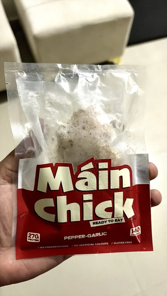 Hand holding a Máin Chick Pepper-Garlic ready-to-eat chicken pack
